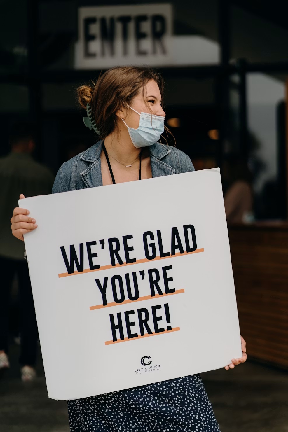 Clinic staff holding a “We're glad you're here!” sign at the entrance