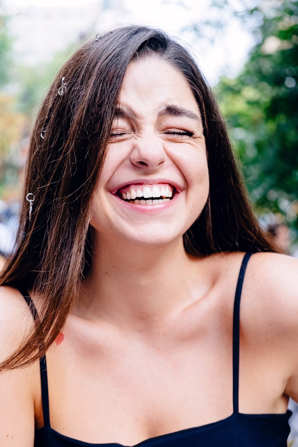 Woman laughing outdoors showing a bright white smile